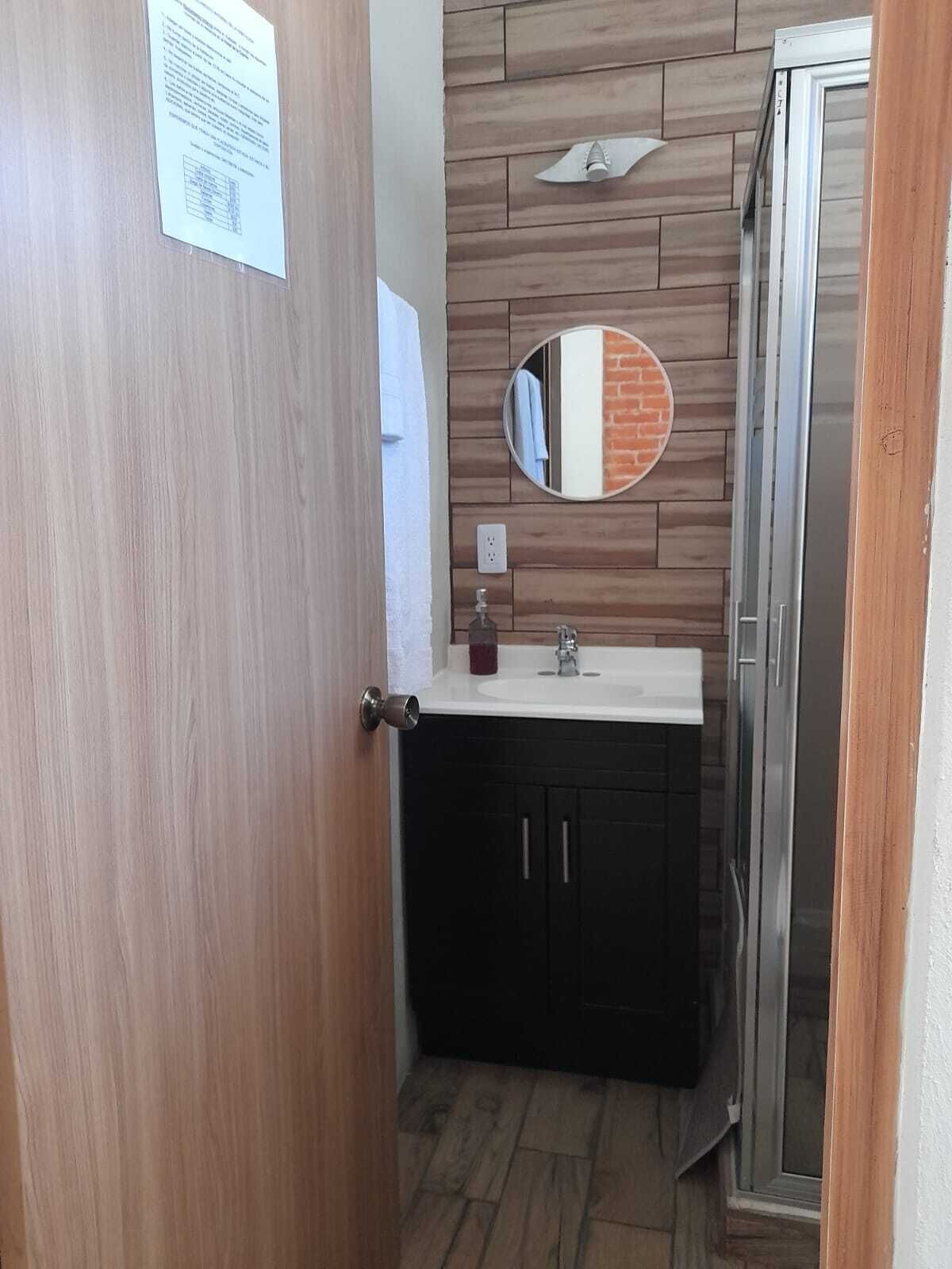 A bathroom with a wooden vanity, a mirror, and a sink.