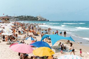 A crowded beach with numerous umbrellas and people enjoying the seaside. - WOM Beach Pod Hotel  (Tel Aviv)