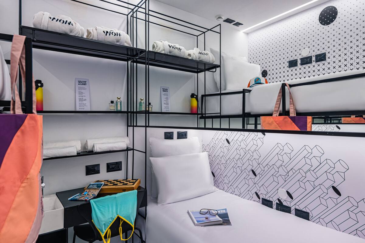 Ein kleines Hotelzimmer mit Etagenbetten, einem Schreibtisch und einem Bett.