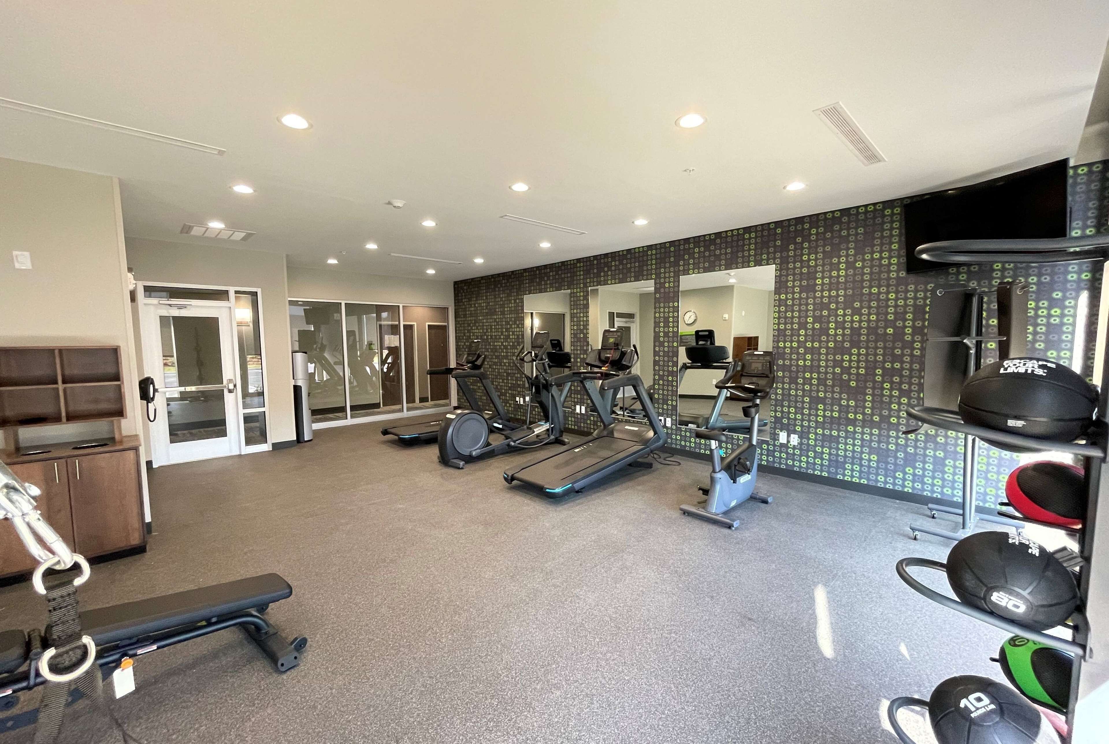 Une salle de sport équipée de tapis de course, de vélos elliptiques et de matériel de musculation.