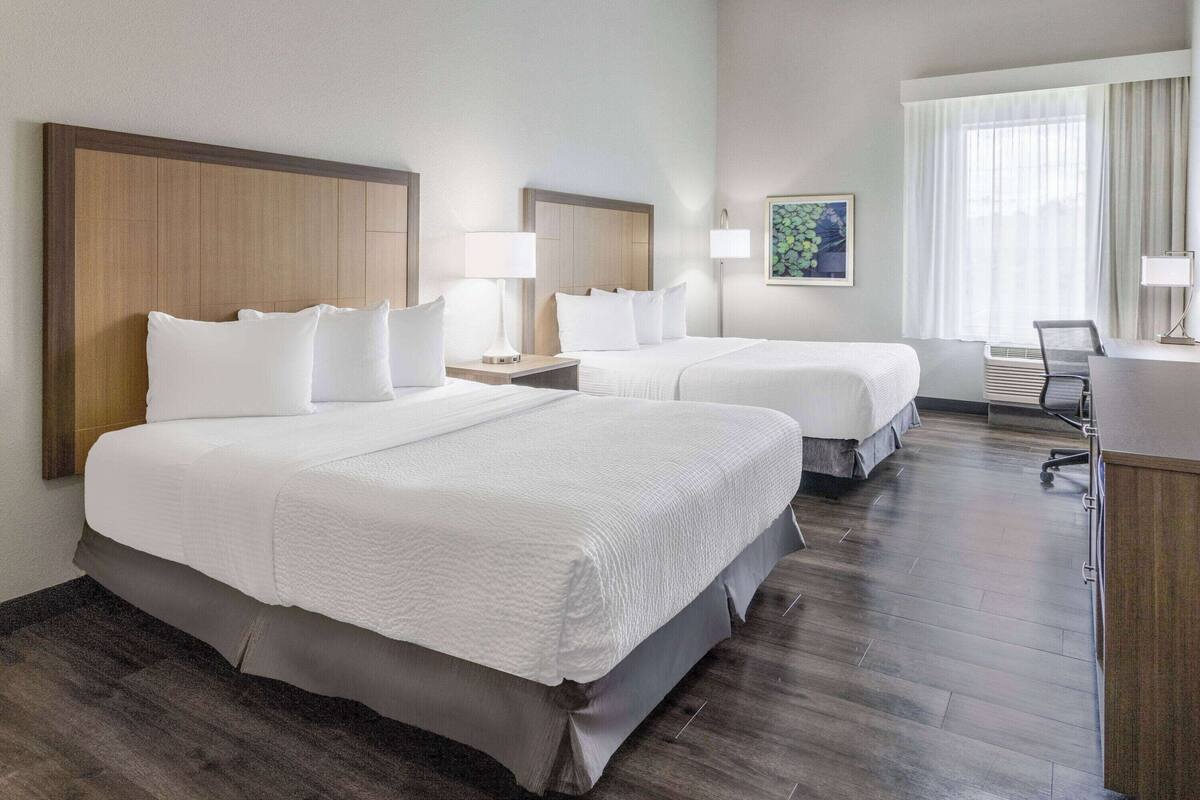 Een hotelkamer met twee bedden, een bureau en een stoel.