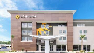 A modern hotel with a prominent sun logo, a central courtyard, and a parking lot.