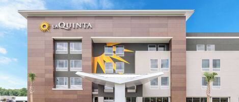 Un hotel moderno con un llamativo logo de sol, un patio central y un estacionamiento.