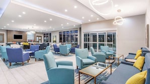 A modern lounge area with multiple seating options, including sofas and armchairs, arranged around a central coffee table. - La Quinta Inn & Suites by Wyndham Valdosta (Valdosta)