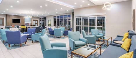 A modern lounge area with multiple seating options, including sofas and armchairs, arranged around a central coffee table.