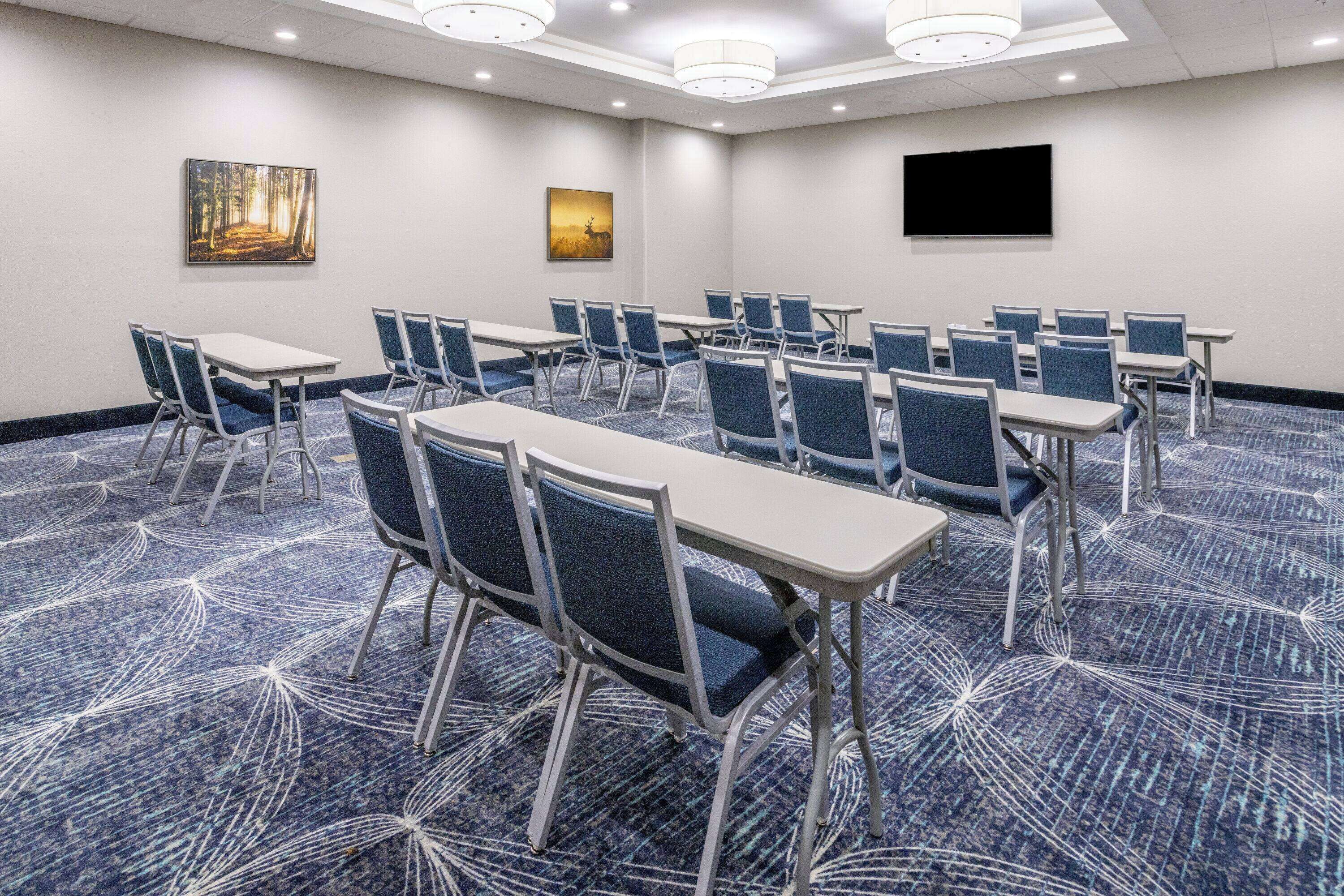 A conference room with tables and chairs, a large screen, and artwork on the walls.