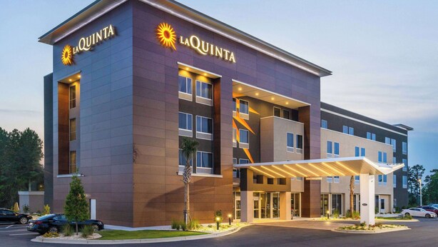 A La Quinta hotel with a modern design, featuring a prominent entrance and a covered outdoor area. - La Quinta Inn & Suites by Wyndham Valdosta (Valdosta)