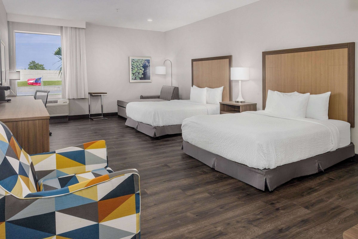 Een hotelkamer met twee bedden, een bureau, een stoel en een raam met uitzicht.