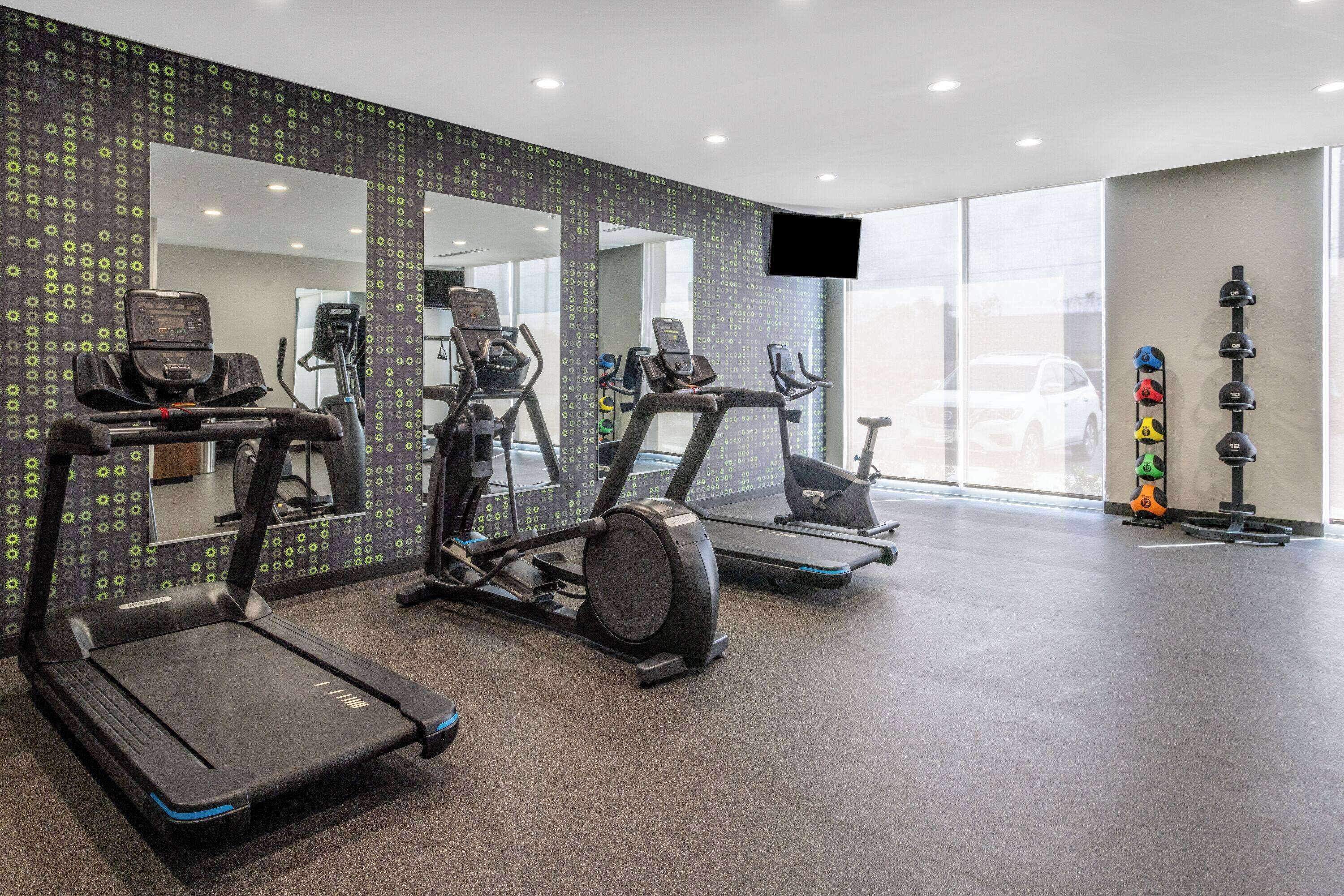 A gym with treadmills, elliptical machines, and a stationary bike.