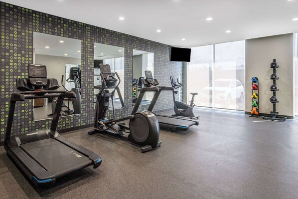 Un gimnasio con cintas de correr, elípticas y una bicicleta estática.