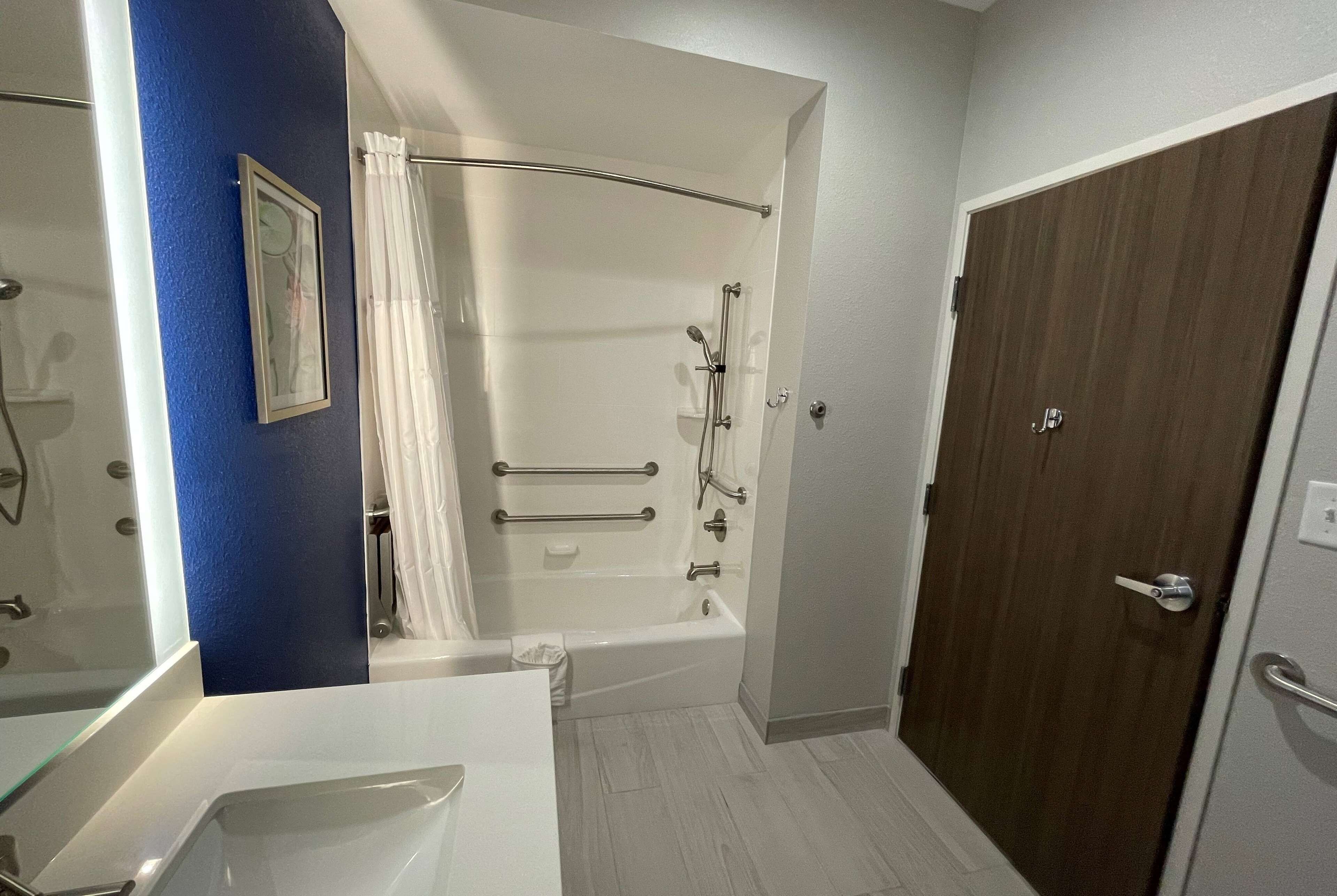 A bathroom with a bathtub, shower, and a door with a handle.