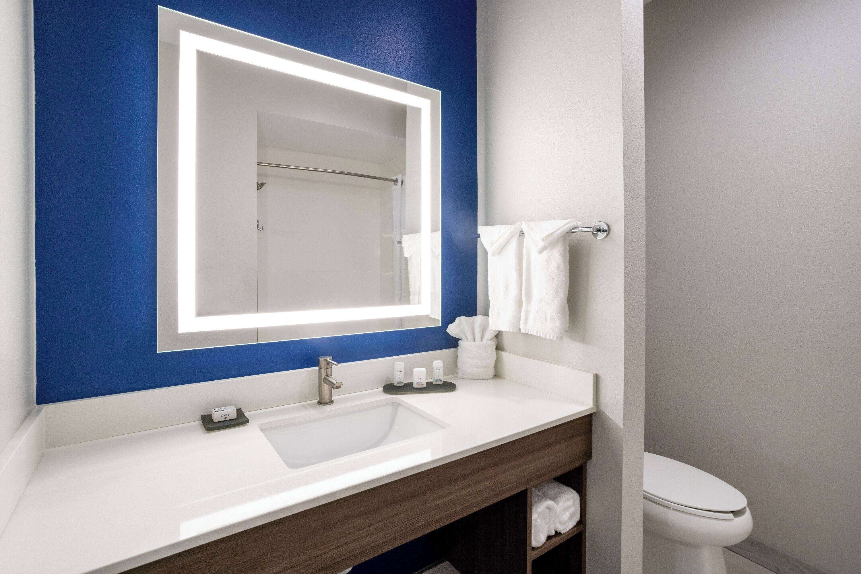 A bathroom with a white sink, a mirror, a towel rack, and a toilet.