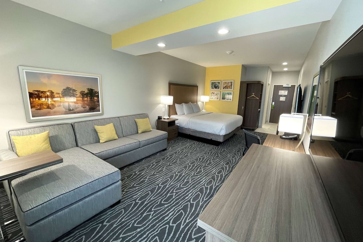 Een hotelkamer met een bed, een bank, een bureau en een spiegel.