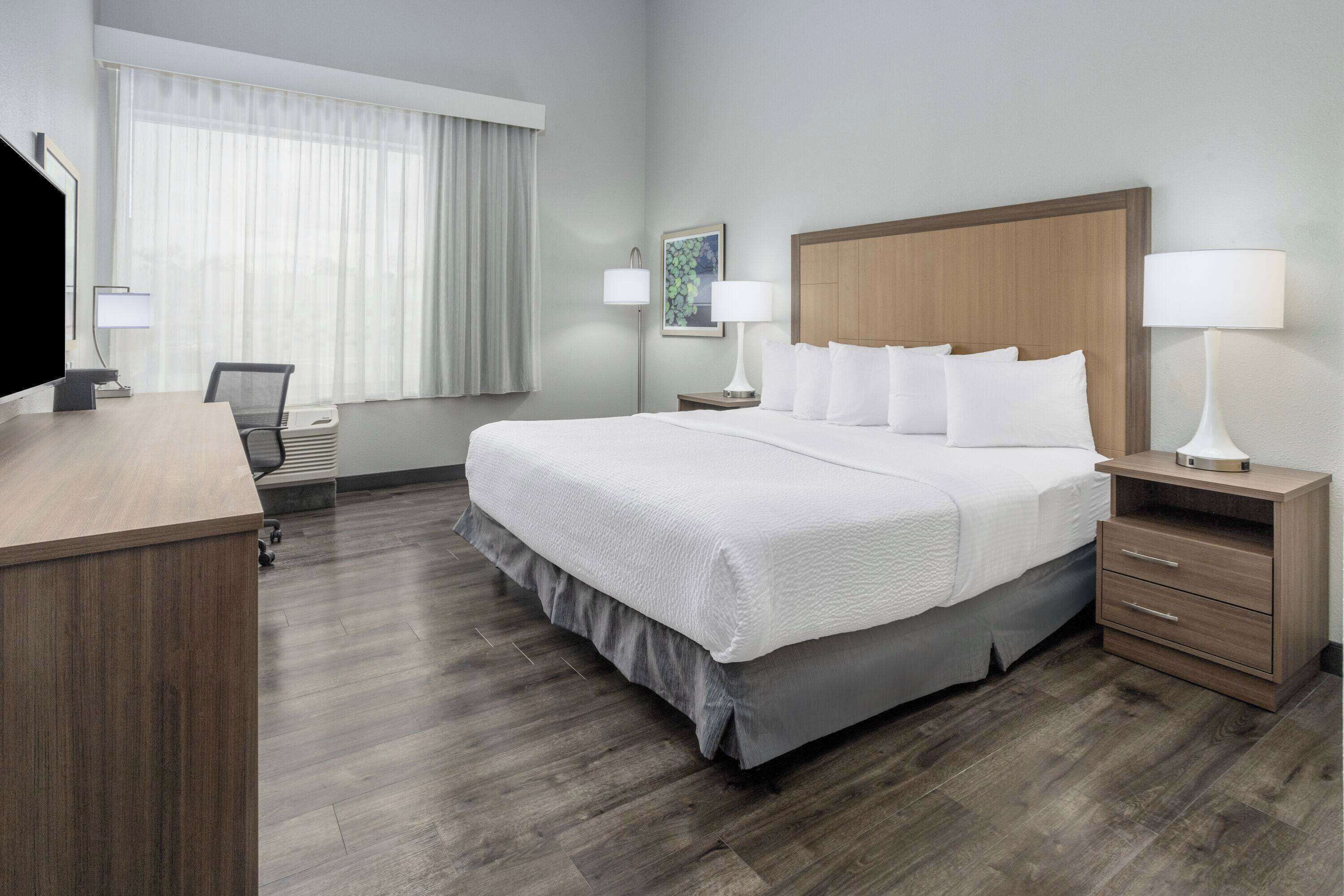 Une chambre d’hôtel avec un grand lit, un bureau, une chaise et un téléviseur.