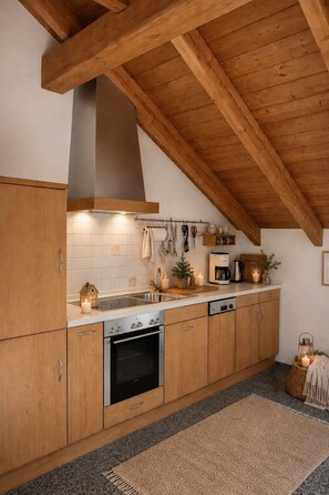 A modern kitchen with wooden cabinets, a built-in oven, and a range hood. - Große Gemütliche Ferienwohnung (Finsterau)