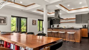 Una cucina moderna con isola centrale, sgabelli da bar e zona pranzo con tavolo e sedie in legno.