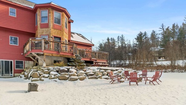 A large, multi-story building with a red exterior and a wooden balcony. There are several red chairs arranged in front of the building. - Luxury 5-BR Mountain Estate 5-Min to Okemo (Ludlow)