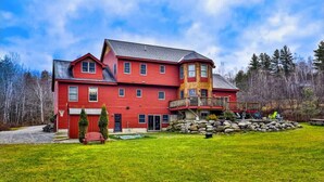 A large, red, multi-story house with a wrap-around porch and a stone foundation. - Luxury 5-BR Mountain Estate 5-Min to Okemo (Ludlow)