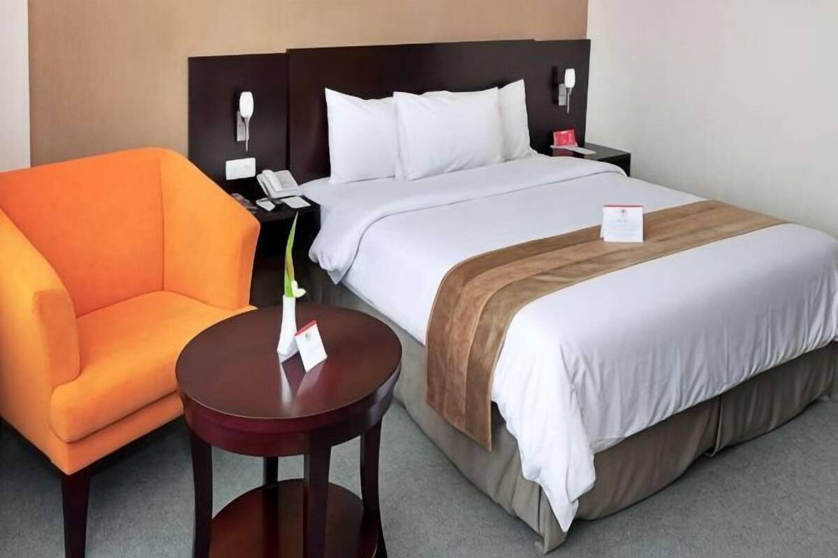 A hotel room with a bed, a nightstand, a chair, and a small table.