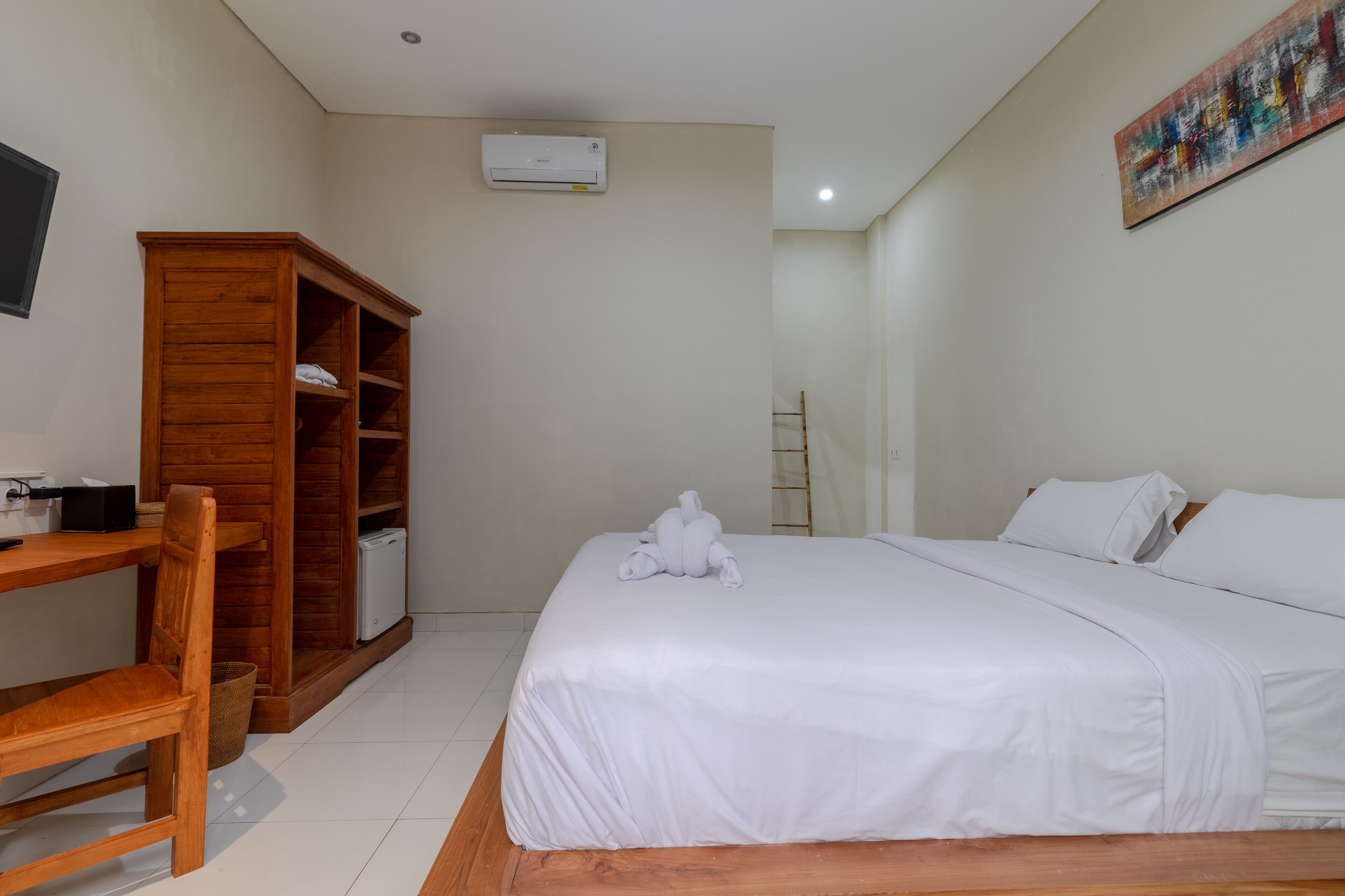 Un dormitorio con una cama, un armario de madera, un escritorio y una silla.