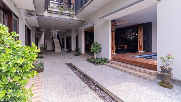 Un edificio moderno con un patio central, una escalera de madera y una pequeña piscina.