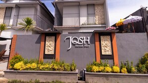 Un edificio con un letrero que dice 'Josh Home Stay' y una pared decorativa.