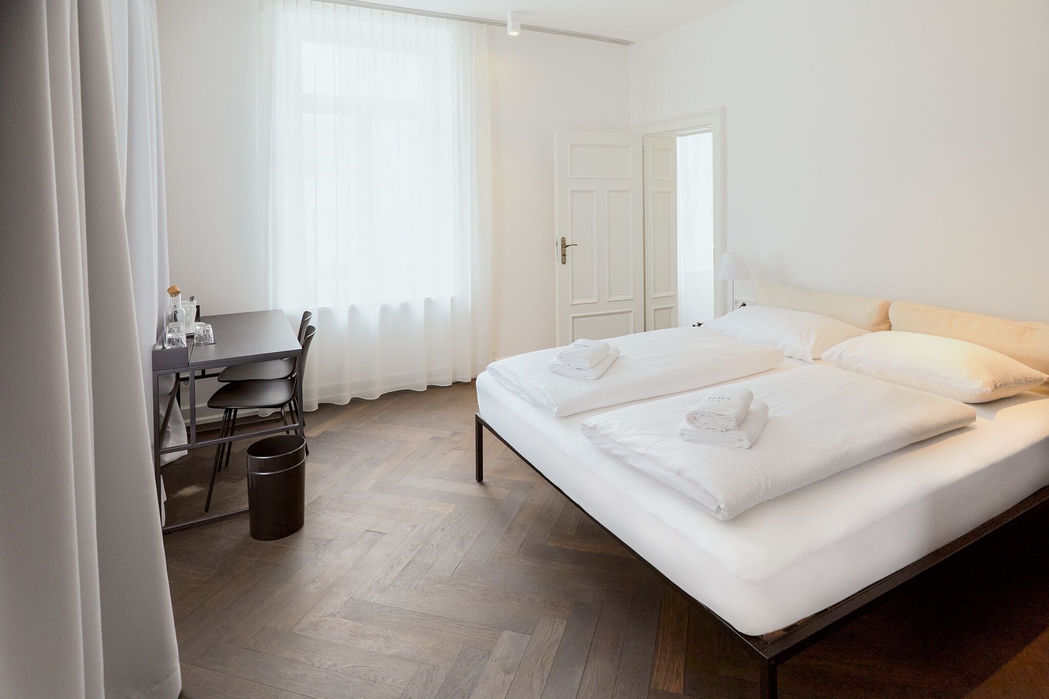 A hotel room with a bed, a desk, and a chair.