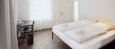 A hotel room with a bed, a desk, and a chair.