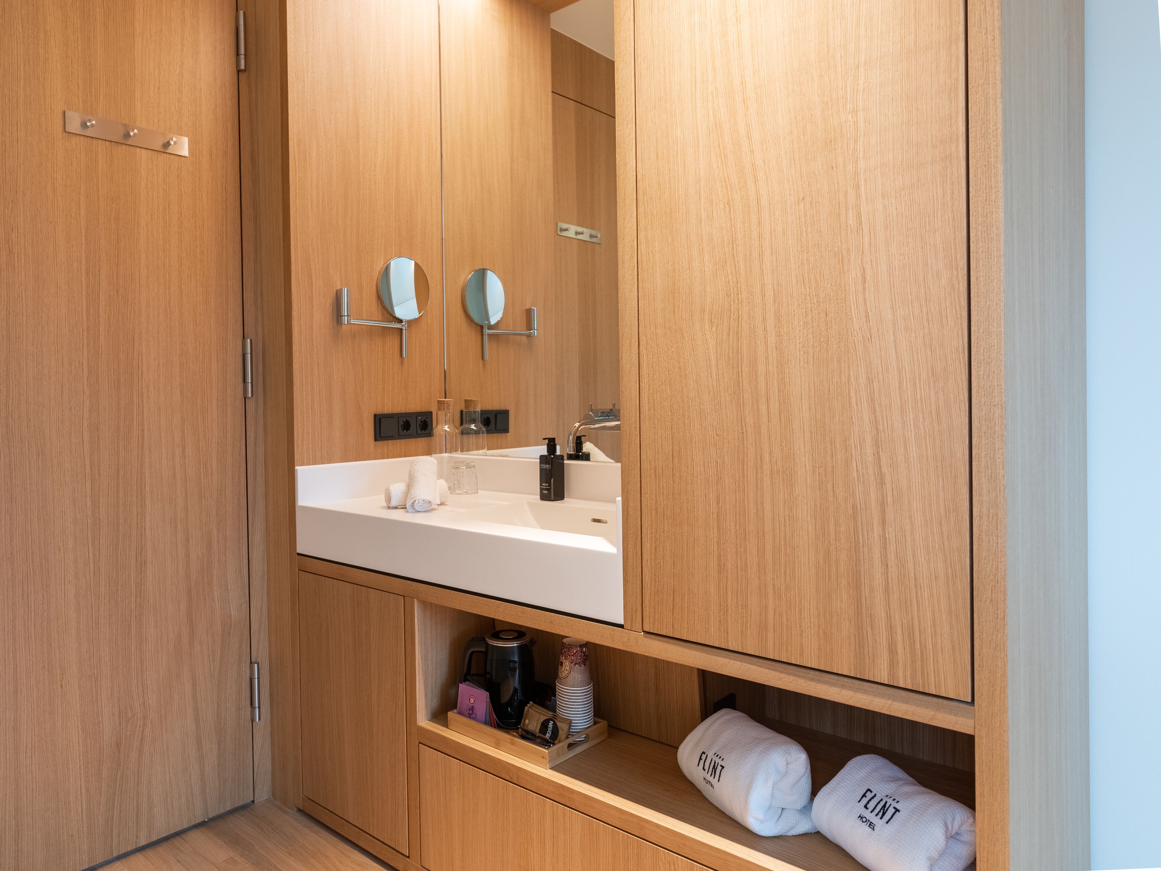A modern bathroom with wooden cabinetry, a white sink, and a mirror.