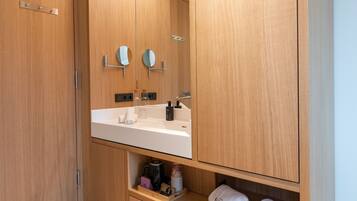 A modern bathroom with wooden cabinetry, a white sink, and a mirror.