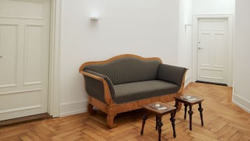 Una stanza con un divano in legno, due tavolini e porte bianche.