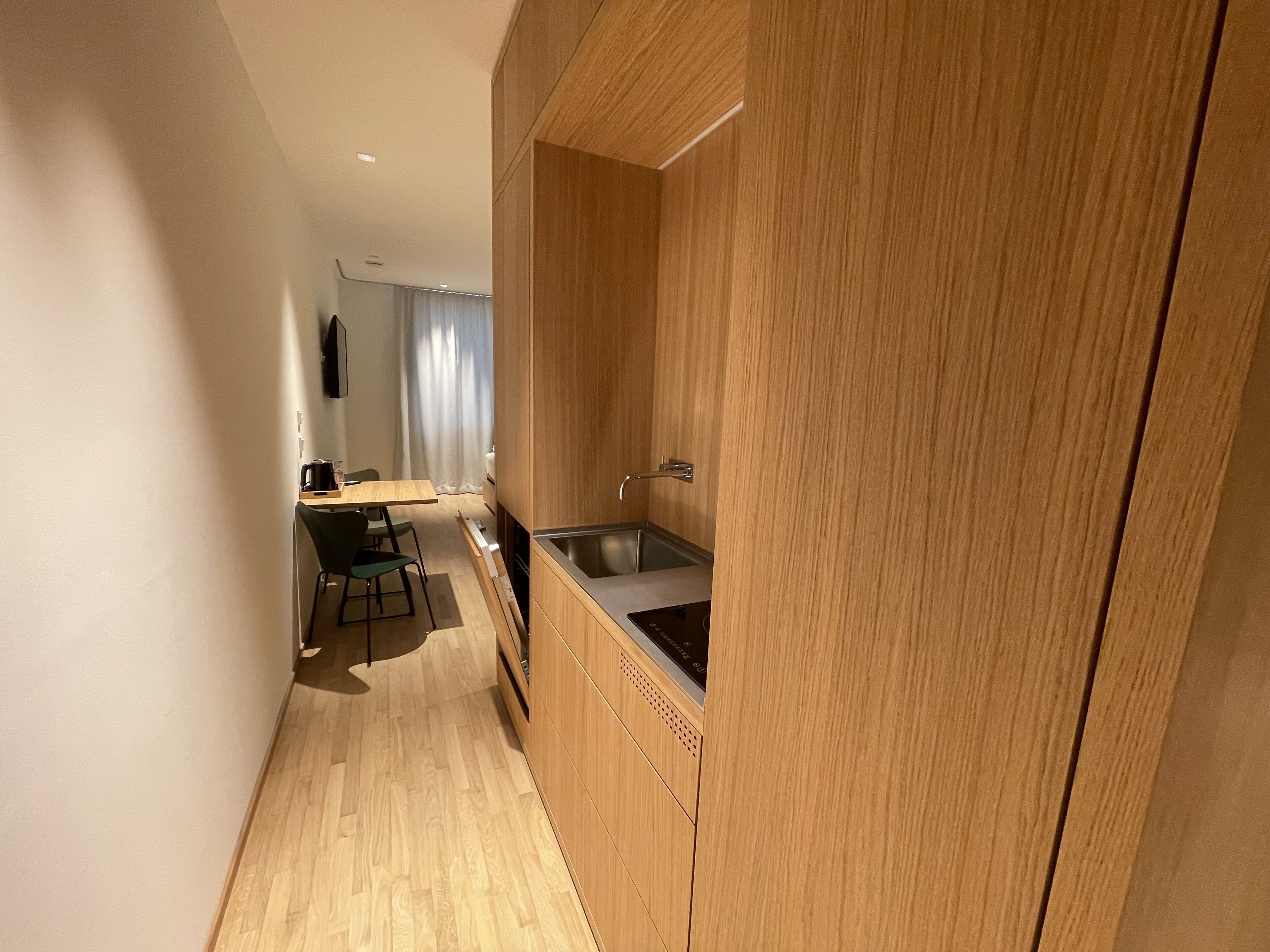 Une cuisine moderne avec des meubles en bois, un évier en acier inoxydable et un coin repas comprenant une table et des chaises.