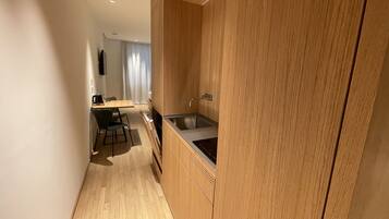 Een moderne keuken met houten kasten, een roestvrijstalen spoelbak en een eethoek met een tafel en stoelen.