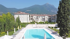 A hotel with a swimming pool, outdoor seating, and mountain views. - Corte Fasanella 31 in Toscolano Maderno (Toscolano Maderno)