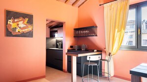 Cocina compacta con comedor, un taburete de bar y una ventana con cortinas.