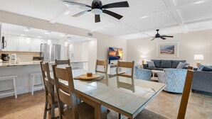 A modern kitchen with white cabinets, a dining table with chairs, and ceiling fans. - Updated Condo with Intracoastal Views & Direct Vehicle Access – Indian Rocks Beach Retreat (Indian Rocks Beach)