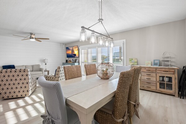 A dining area with a large table, chairs, and a ceiling fan.