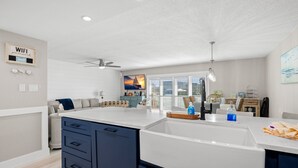 Een moderne keuken met een groot eiland, witte aanrechtbladen en blauwe keukenkastjes.