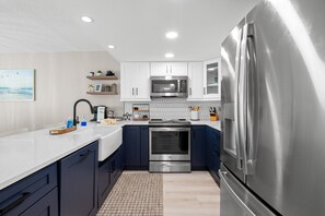 A modern kitchen with white cabinets, a stainless steel refrigerator, and a microwave.