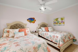 A bedroom with two beds, a ceiling fan, and a wall painting.