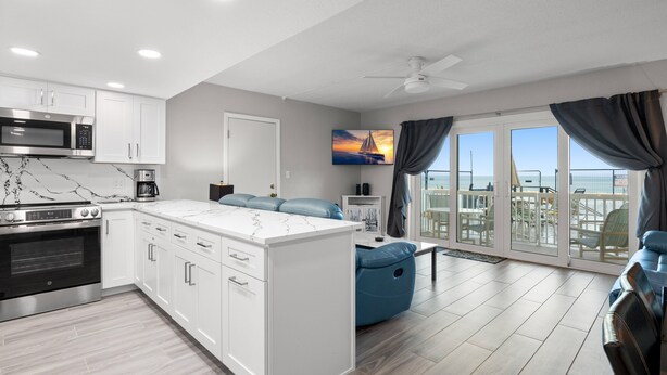 A modern kitchen with white cabinets, a built-in oven, and a microwave.