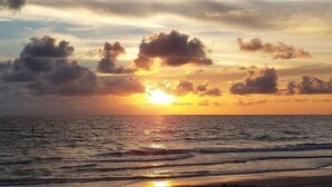 A sunset over the ocean with clouds and waves.