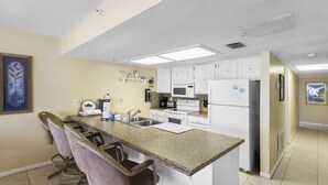 A kitchen with a granite countertop, white cabinets, a microwave, stove, and a refrigerator. - Spacious 2BR Intracoastal View Condo – Discounted Rate  No Balcony, Full Comfort Sleeps 6 (Indian Rocks Beach)