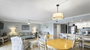 Amplia sala de estar con una mesa de comedor, sillas y una cocina al fondo.