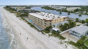 Ett hotell vid stranden med flera vÄningar, en swimmingpool och utsikt över stranden och floden.