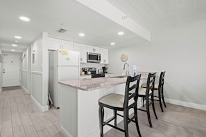 A modern kitchen with white cabinetry, a granite countertop, and a built-in microwave.