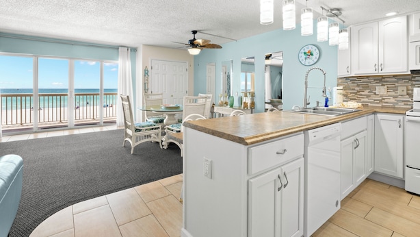 A kitchen with white cabinets, a wooden countertop, and a view of the ocean. - Coastal Charm & Sunset Views from Your Beachfront Balcony at Fifty Gulfside – Indian Rocks Beach (Indian Rocks Beach)