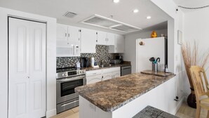 A modern kitchen with white cabinets, a granite countertop, and stainless steel appliances.