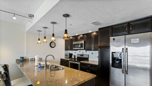 Eine moderne Küche mit Granit Arbeitsplatten, Edelstahlgeräten und Pendelleuchten.