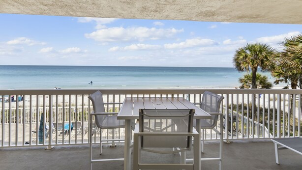 A balcony with a table and chairs overlooking a beach. - Corner Retreat with Gulf & Intracoastal Views from Wraparound Balcony at Fifty Gulfside (Indian Rocks Beach)